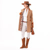 A woman modeling the Welligogs Damelza Camel Coat - a mid-length camel coat with brown leather trim and a poppy floral lining, styled with a brown hat, white shirt and pants, brown boots, and carrying a brown handbag against a white background.