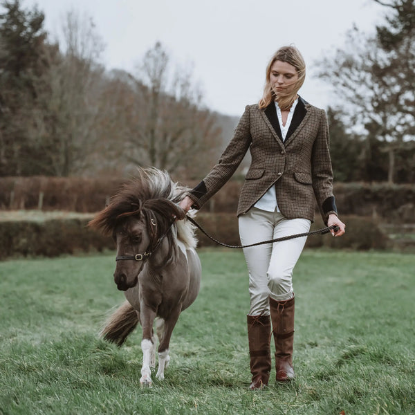 Grantham Sage Check Wool Jacket by Welligogs, full-length outdoor view on a model leading a pony, showing the tailored silhouette.