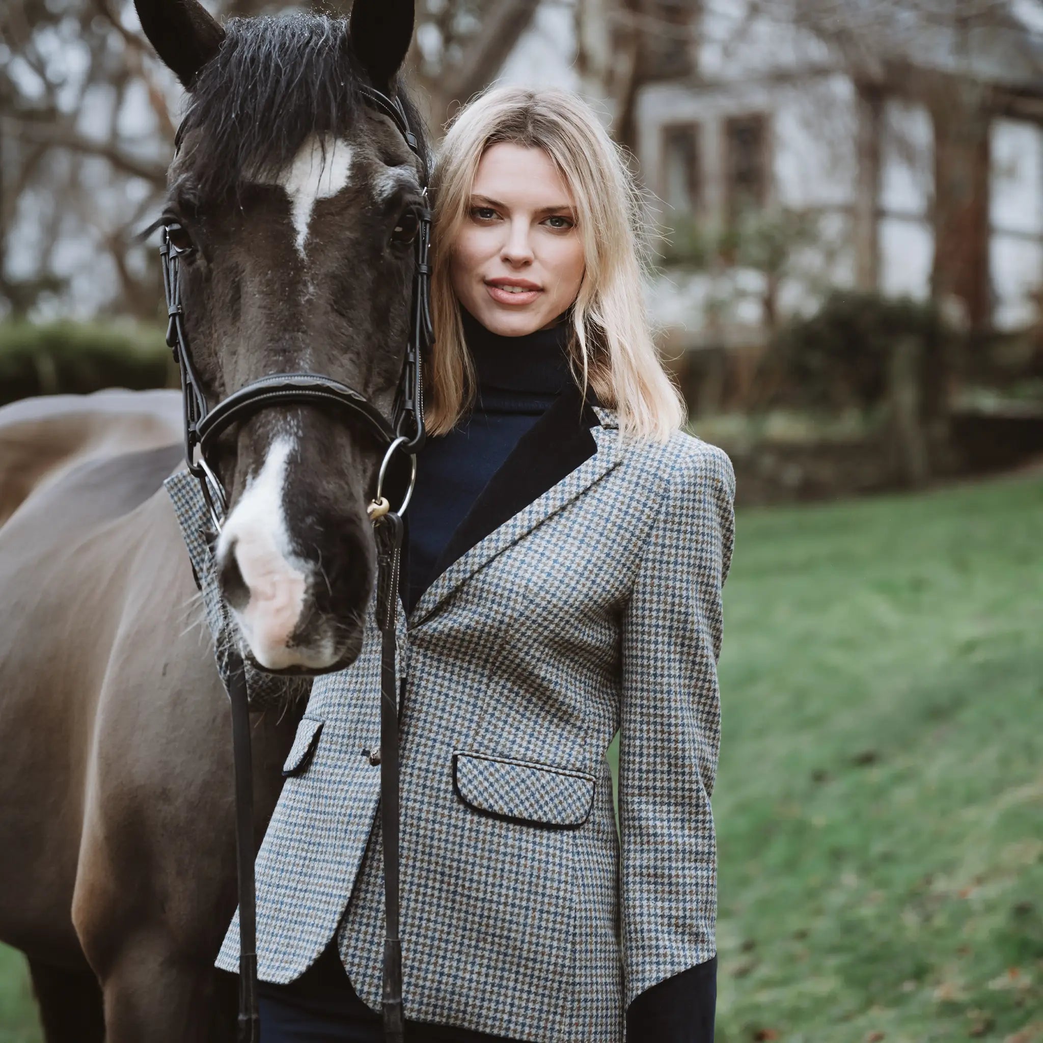Grantham Midnight Check Wool Jacket by Welligogs, worn by a model beside a horse outdoors, showing velvet lapels and trimmed flap pockets.