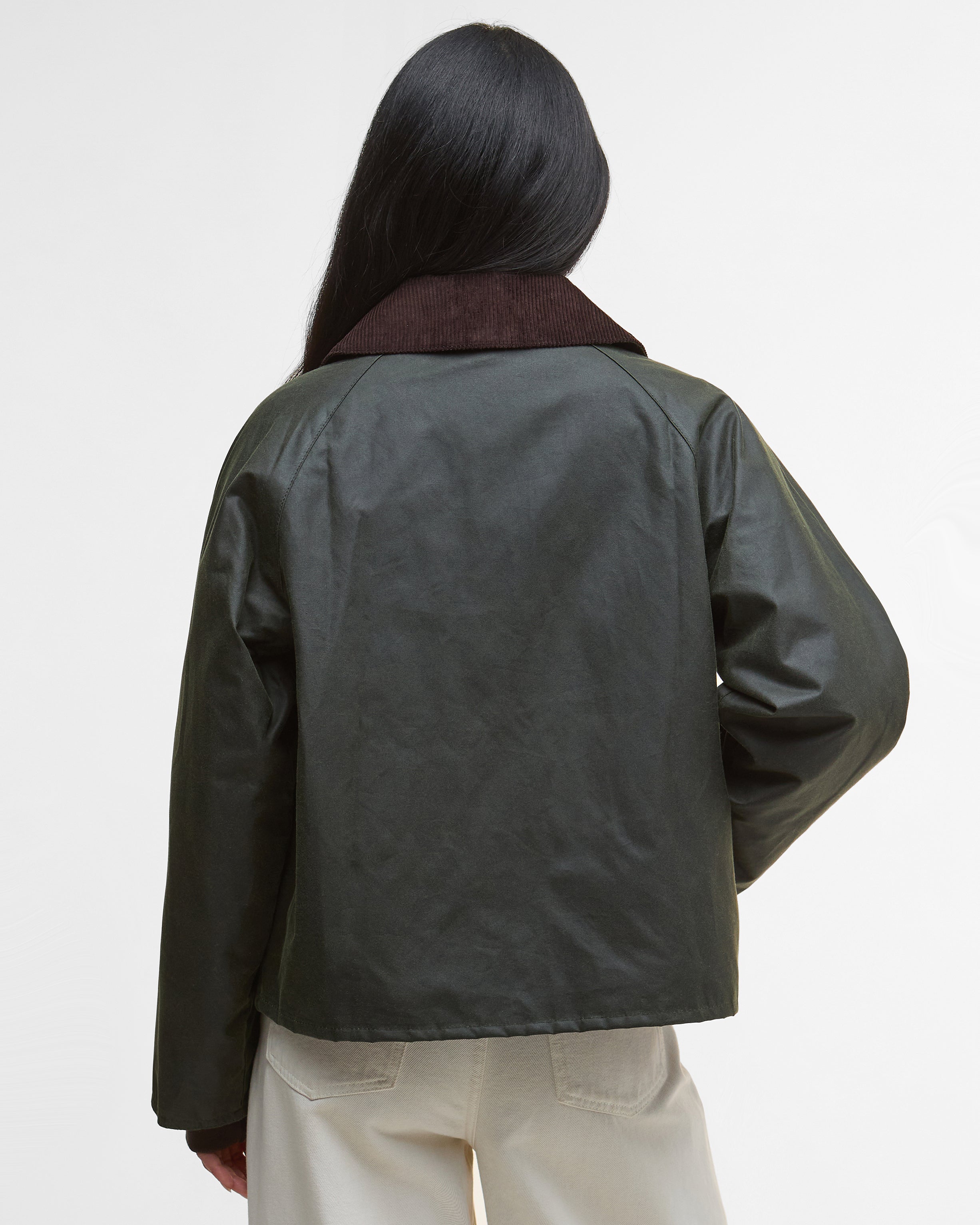 Person wearing a dark green jacket with a plain background