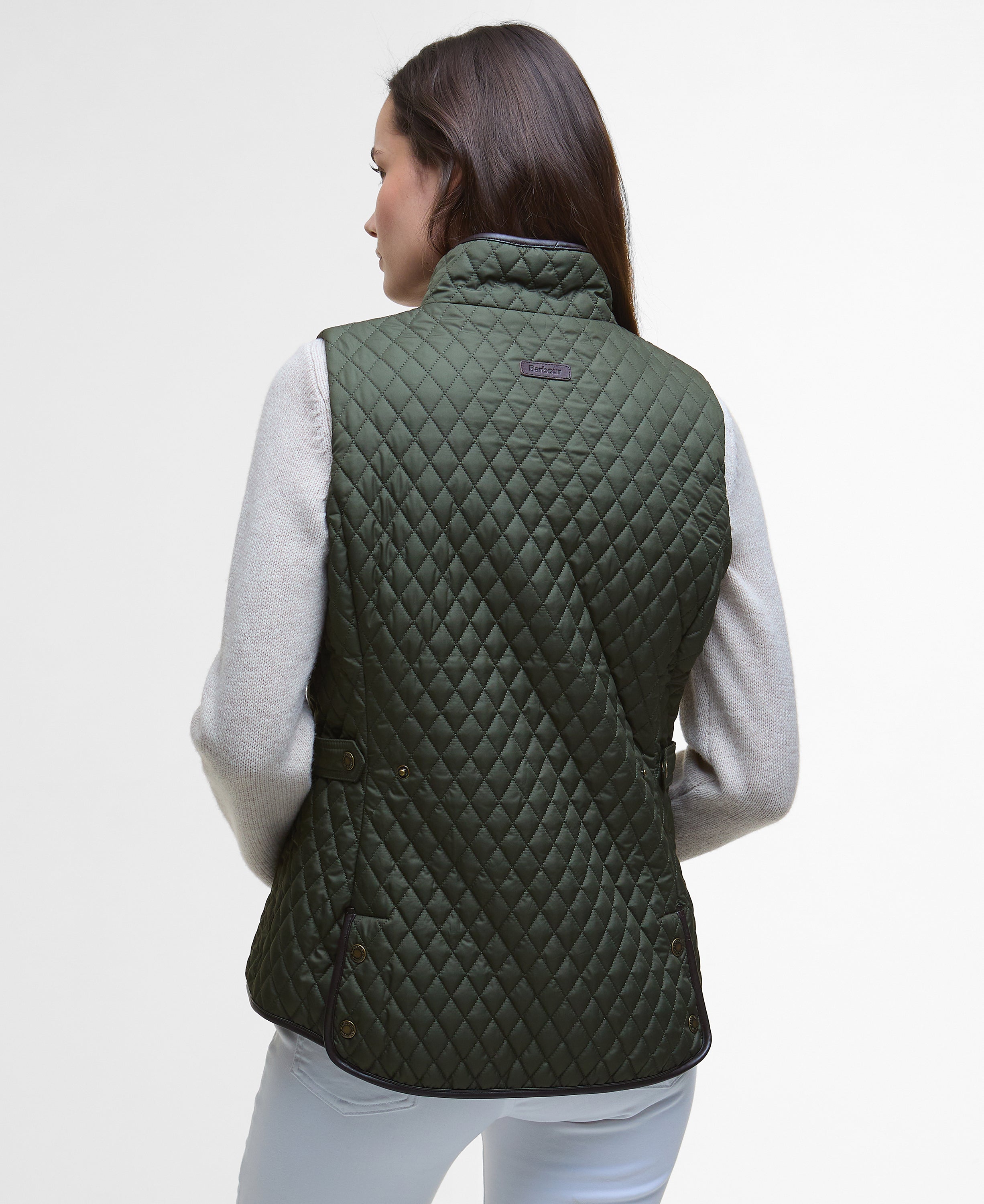 Person wearing a green quilted vest on a light gray background
