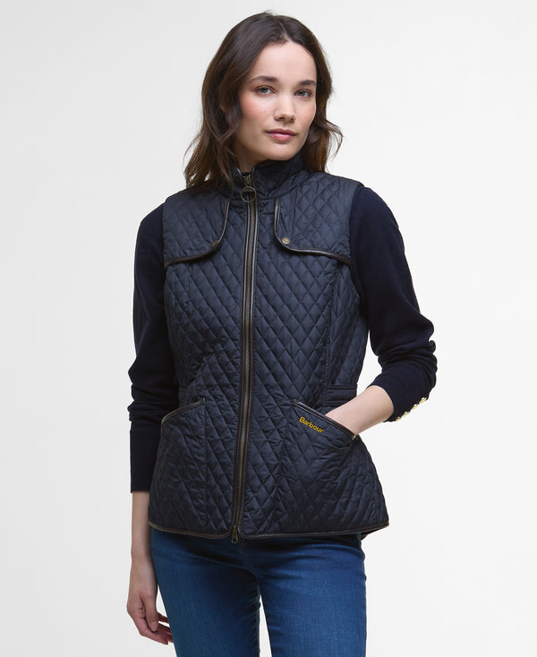 Woman wearing a navy quilted vest on a light gray background