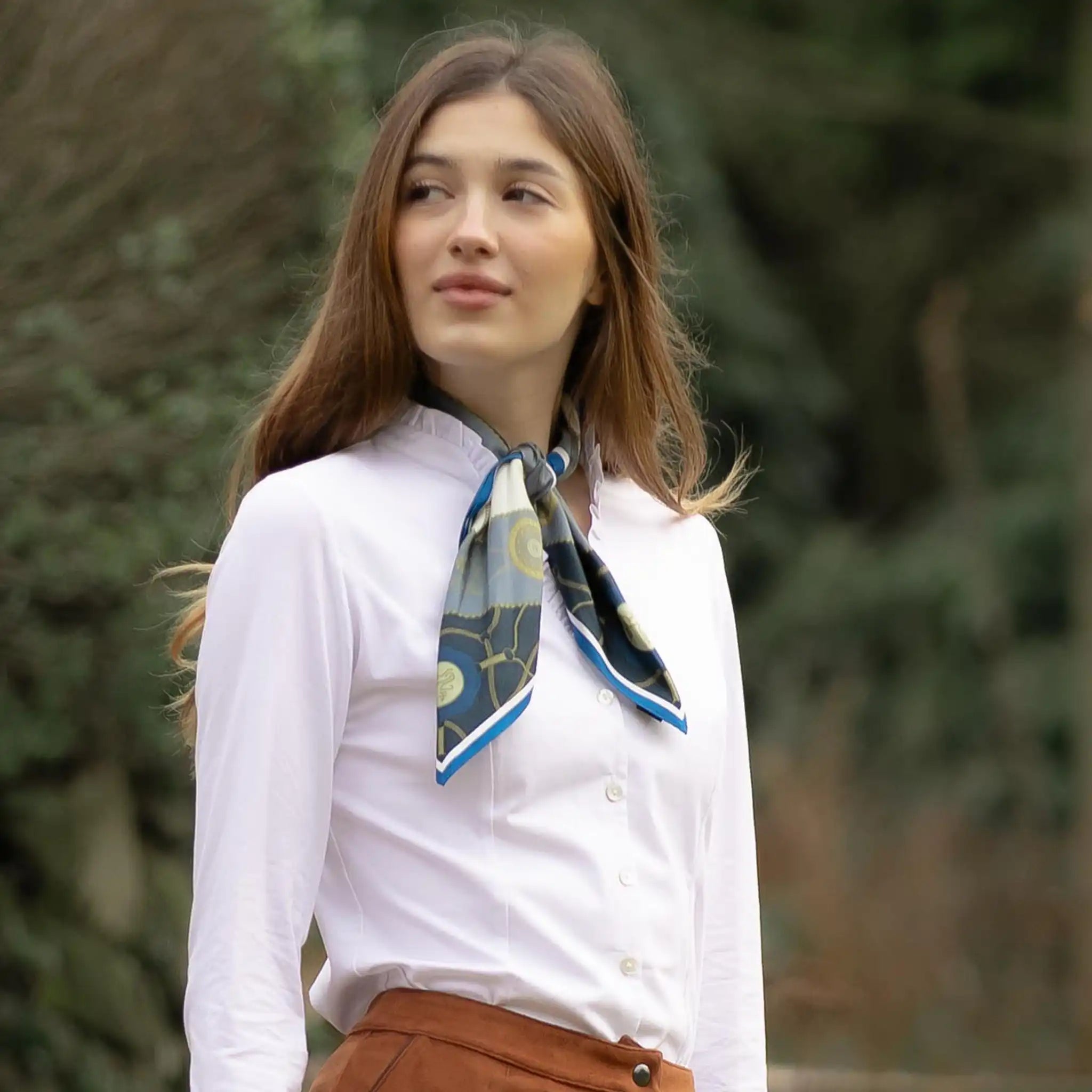 Woman wearing a white shirt with a patterned scarf outdoors