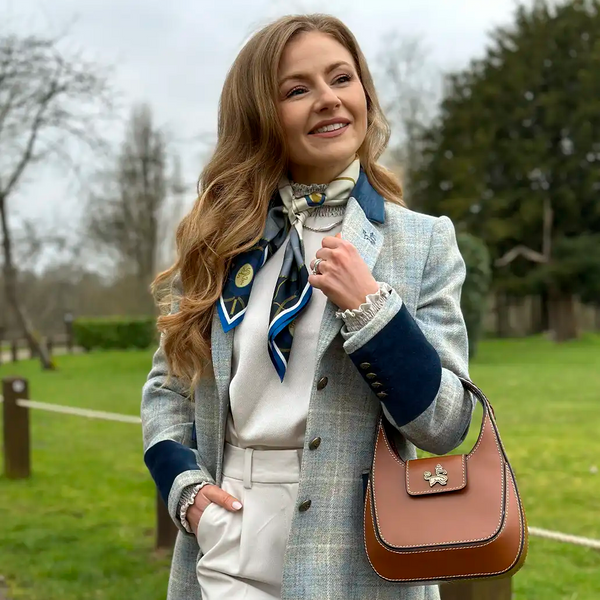 Woman in formal attire with a plaid coat and brown handbag outdoors