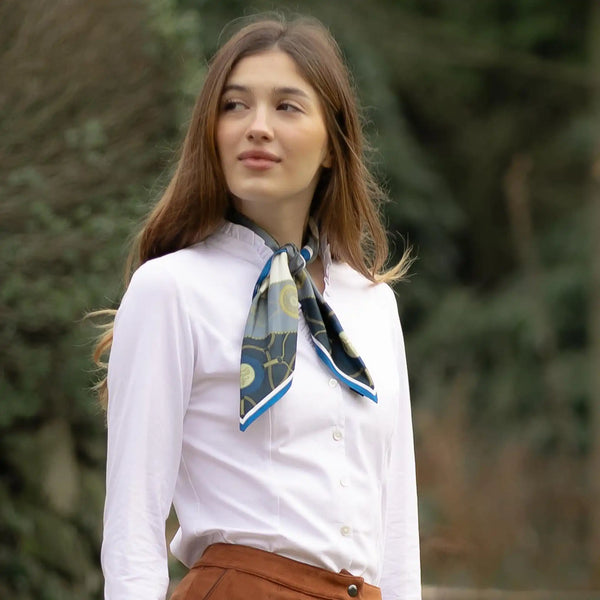 Woman wearing a white shirt with a patterned scarf outdoors