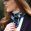 Woman wearing a blue patterned scarf around her neck with a blurred background