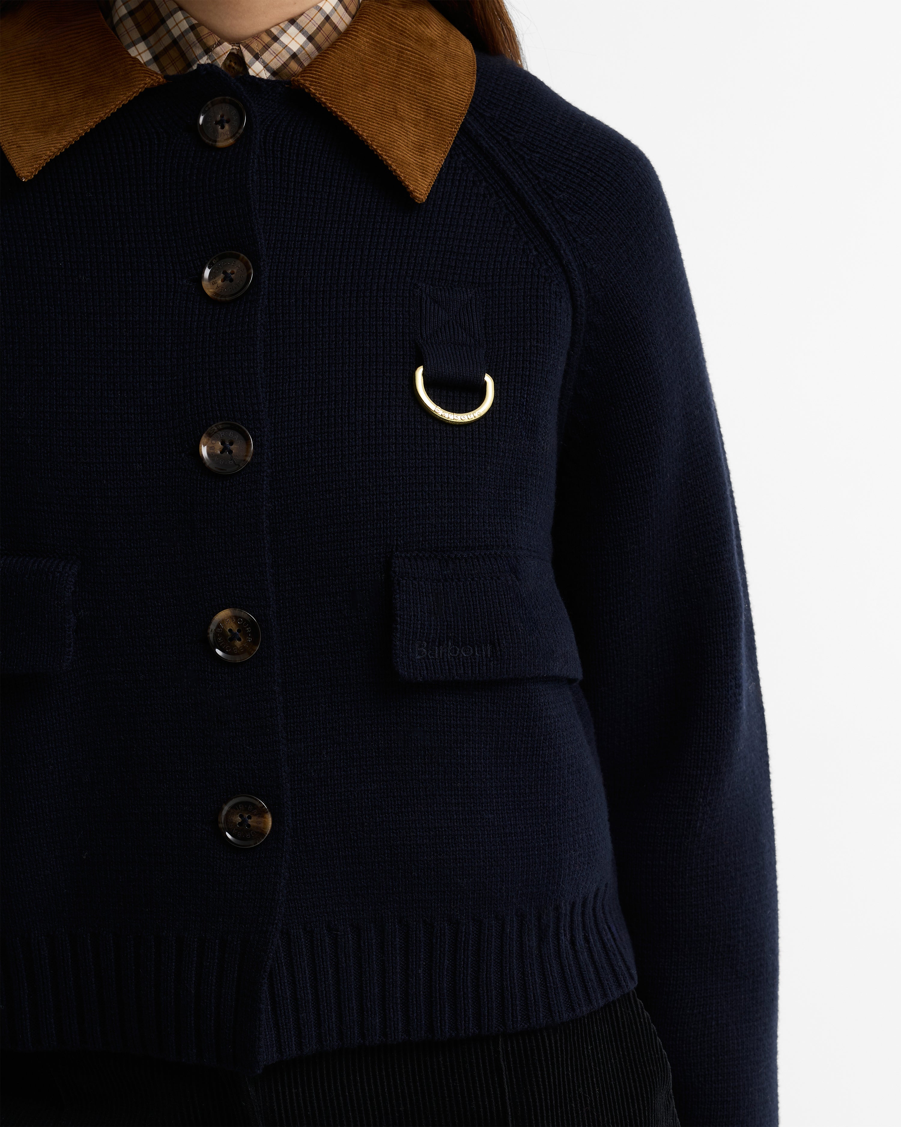 Navy blue cardigan with brown collar and gold emblem on a white background