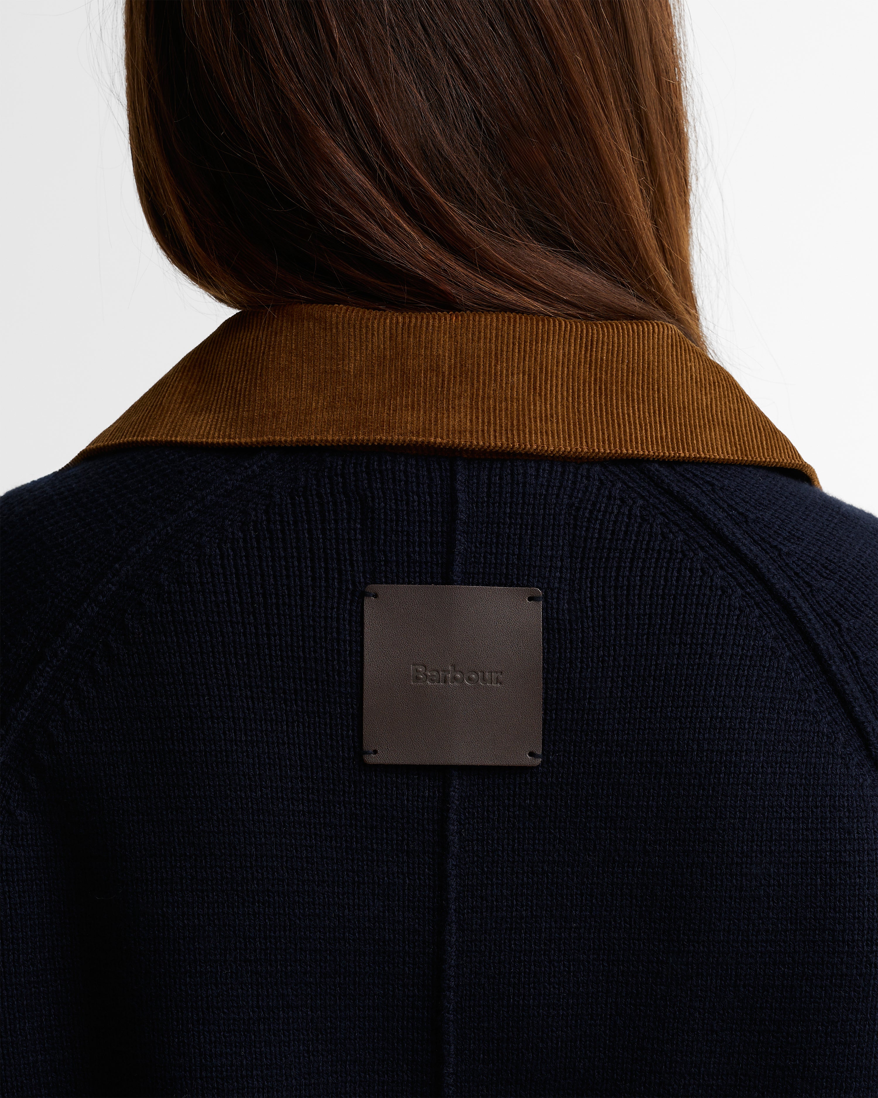 Person wearing a dark jacket with a Barbour label on a white background