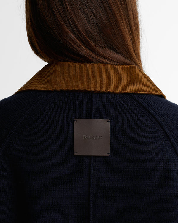 Person wearing a dark jacket with a Barbour label on a white background