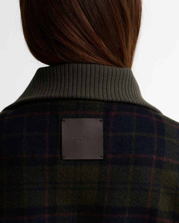 Close-up of the Barbour Ivybridge Overshirt showing the embossed leather Barbour patch on the upper back, above the shadow tartan body and ribbed collar.