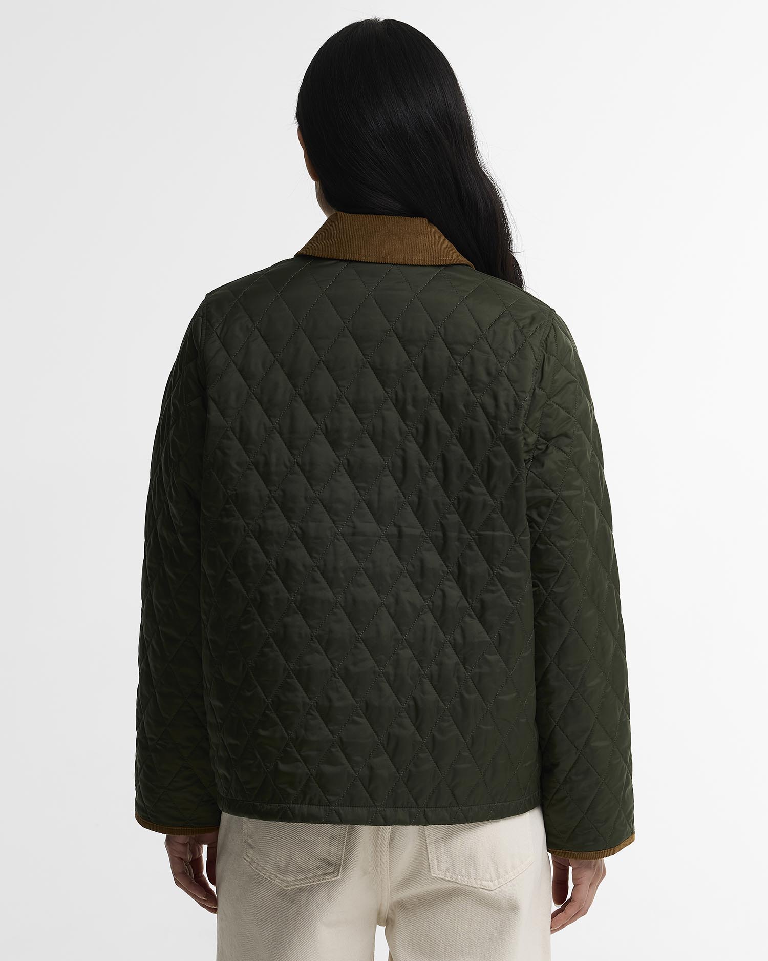 A person shown from the back wearing a dark olive green diamond-quilted jacket with a contrasting brown collar, paired with light beige pants, against a plain white studio background.