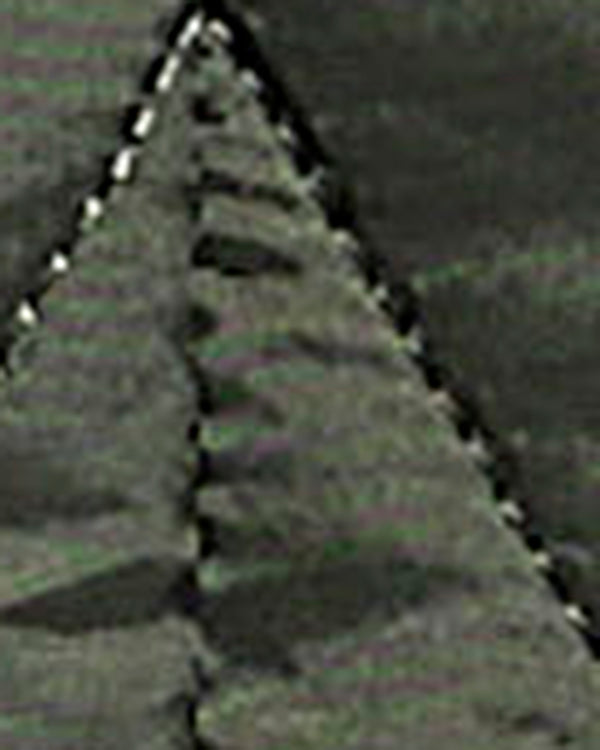 A close-up, low-resolution view of a textured gray surface with a triangular pattern and a dashed white line along the left edge.
