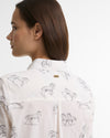 A woman shown from the back wearing a white button-up shirt with a gray horse pattern and a small gold Barbour brand plaque on the collar.