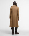 A woman viewed from behind wearing a mid-length camel brown trench coat, dark brown knee-high boots, and white tights against a plain white studio background.