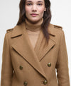 A woman wearing a camel brown double-breasted coat over a matching beige turtleneck sweater, photographed against a clean white studio background.