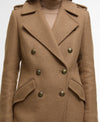 A close-up of a camel brown double-breasted coat with dark metallic buttons, worn over a matching beige turtleneck sweater.