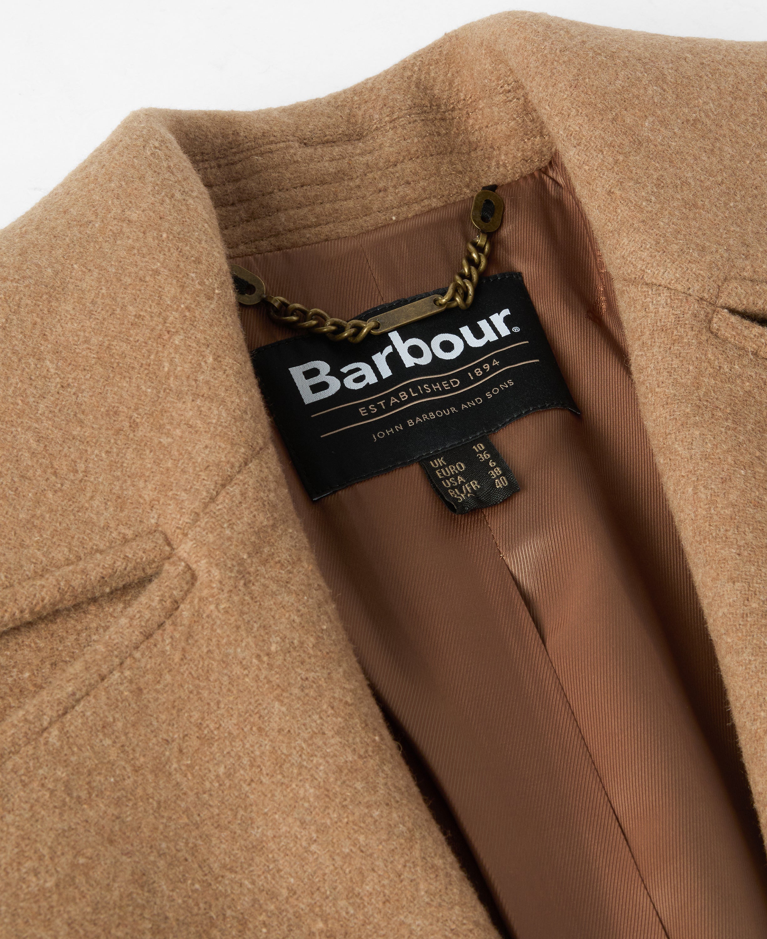 Close-up of a camel-colored wool coat with a visible Barbour brand label inside the collar.