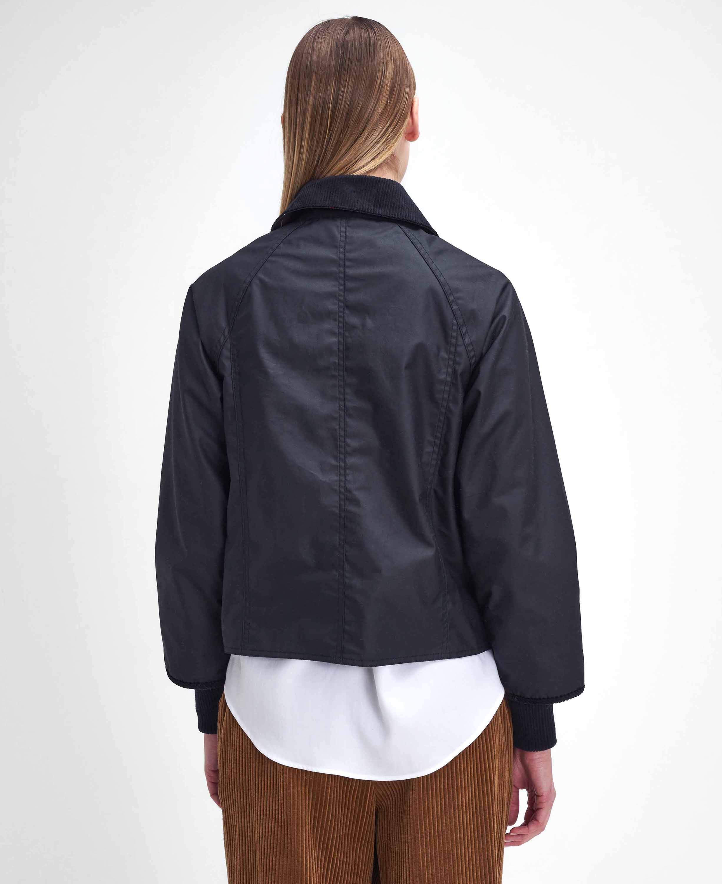 Person wearing a dark jacket over a white shirt and brown pants on a white background