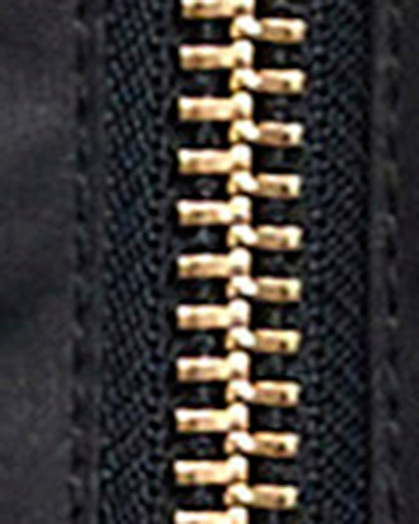 Close-up of a black zipper with gold-toned metal teeth on a dark textured fabric background.