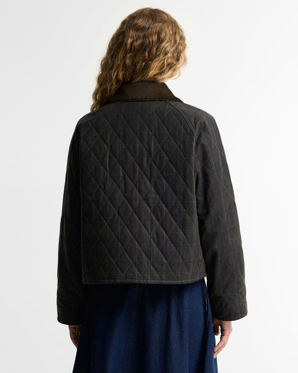 A model shown from the back wearing a dark olive diamond-quilted jacket with a dark brown collar, paired with a navy blue skirt, against a plain white studio background.
