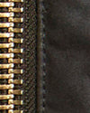 Close-up detail of a zipper with shiny gold-toned teeth and a dark textured fabric surface.