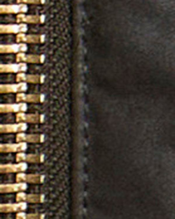 Close-up detail of a zipper with shiny gold-toned teeth and a dark textured fabric surface.