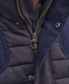 Close-up of a Barbour quilted vest with dark navy waxed cotton canvas, textured navy blue fabric panels, and a bronze-toned metal zipper with a circular ring pull.