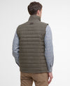 Man wearing a green puffer vest over a checkered shirt on a light gray background