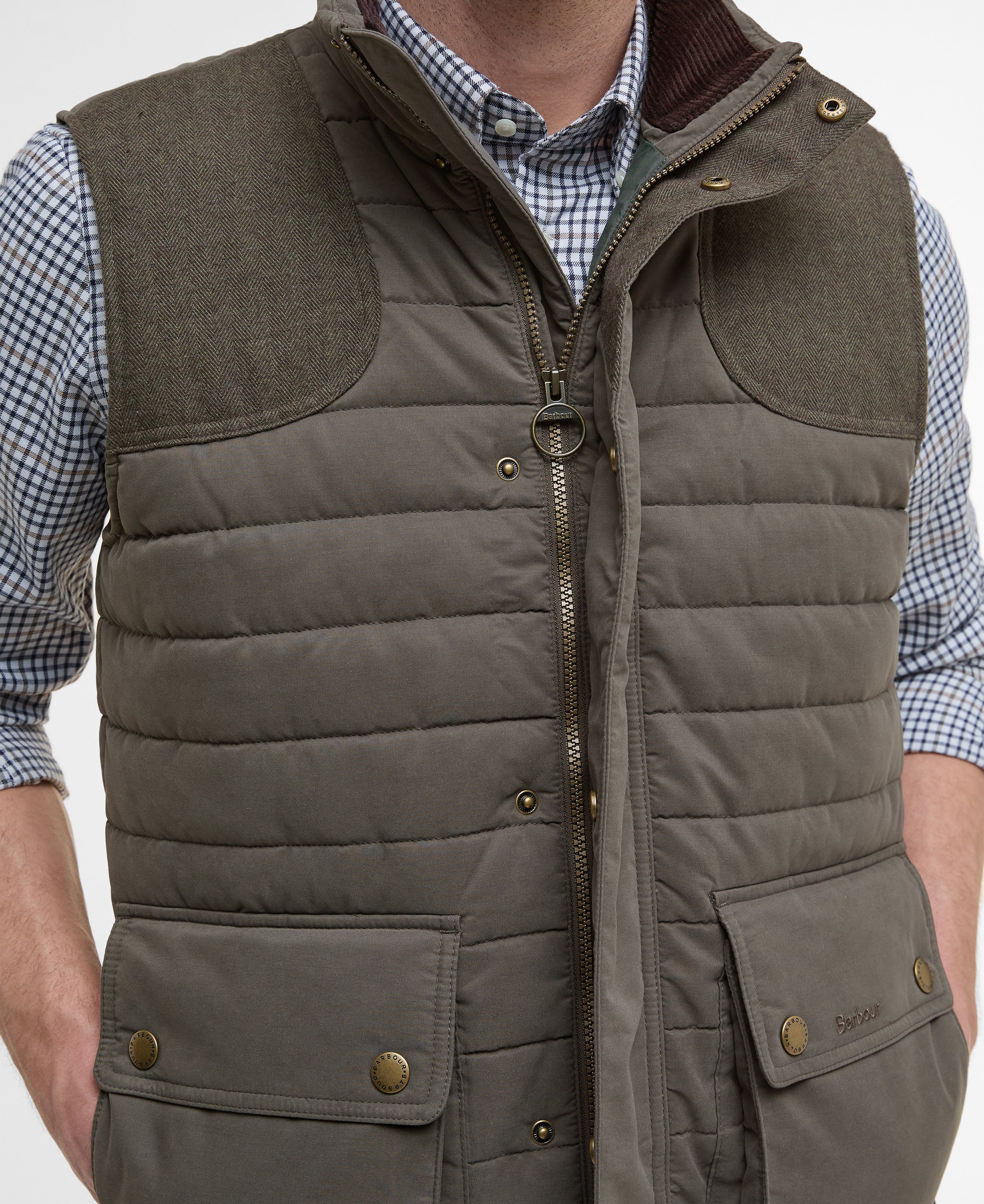 Brown quilted vest worn over a checkered shirt on a white background