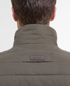 Close-up back view of a person wearing a quilted Barbour jacket in olive green, showing the high collar and the Barbour brand patch on the upper back.