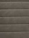 A close-up of a quilted fabric texture in a muted taupe-gray color, showing horizontal stitching and a soft, padded surface.