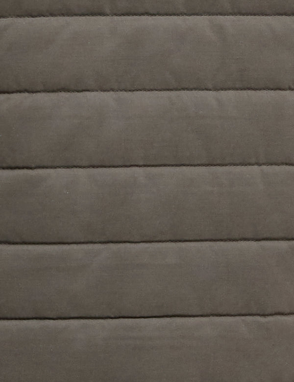 A close-up of a quilted fabric texture in a muted taupe-gray color, showing horizontal stitching and a soft, padded surface.