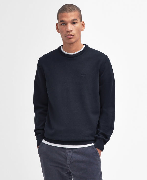 Man wearing a navy blue sweater with a white collar on a light gray background