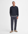 Man wearing a navy sweater and gray pants on a white background