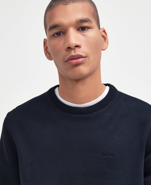 Man wearing a navy sweater against a plain background