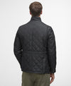 Person wearing a black quilted jacket on a white background