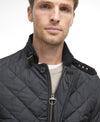 Man wearing a quilted black jacket on a white background