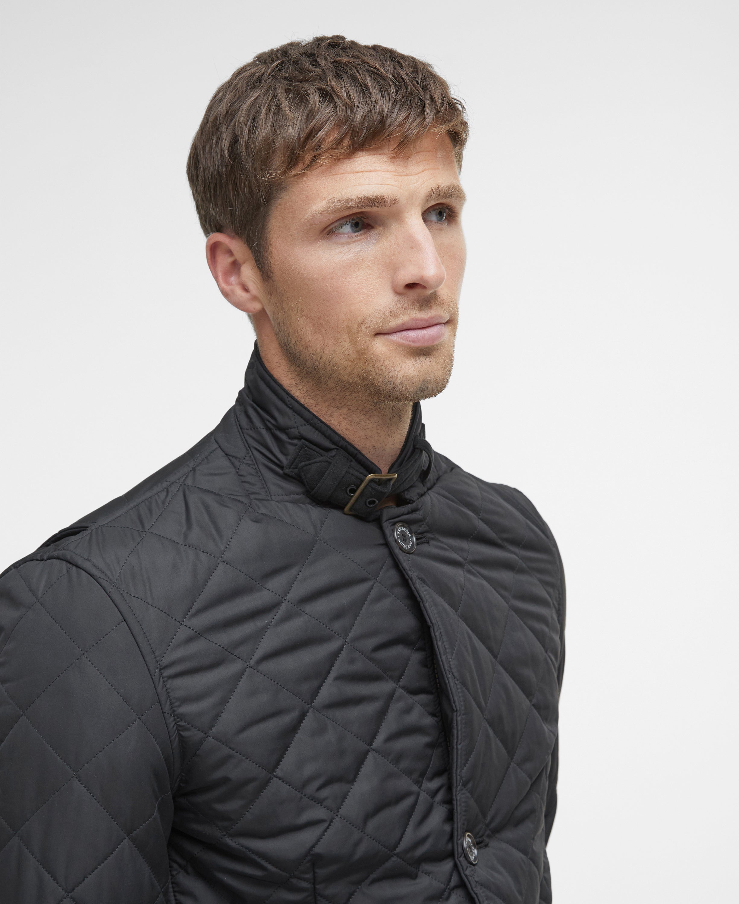 Man wearing a black quilted jacket against a light gray background