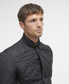 Man wearing a black quilted jacket against a light gray background