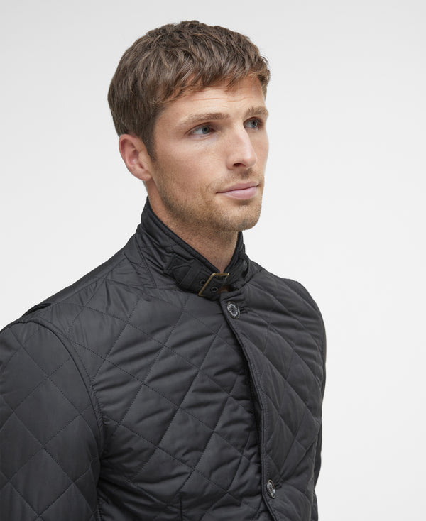 Man wearing a black quilted jacket against a light gray background