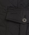 Close-up of a black quilted Barbour jacket showing a pocket flap with the Barbour logo and a round button.