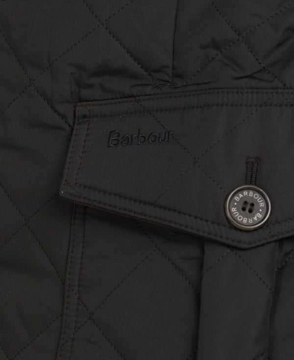 Close-up of a black quilted Barbour jacket showing a pocket flap with the Barbour logo and a round button.