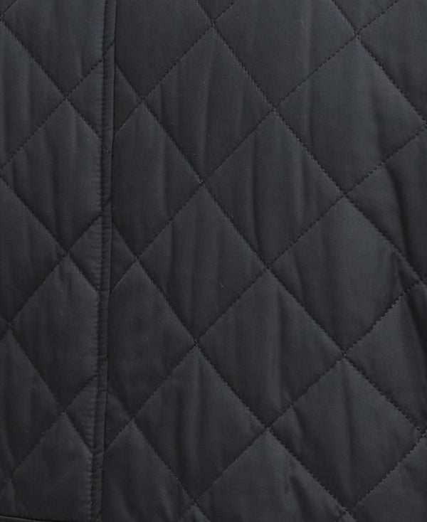 Close-up of a black quilted jacket fabric showing a diamond patterned stitching.