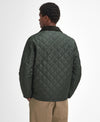 A man shown from the back wearing a dark olive green diamond-quilted jacket with a black collar, paired with tan pants, against a plain white studio background.