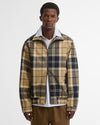 A man wearing a Barbour Tartan Showerproof Blouson Jacket over a white collared shirt and brown trousers.