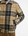 A close-up of a men's Barbour Tartan Showerproof Blouson Jacket, worn by a model. The jacket features a full-zip front, a stand-up collar, and side pockets.