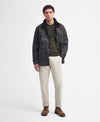 Model wearing the Barbour Sapper Wax Jacket styled for a complete outfit: green shirt, beige pants, and brown boots.