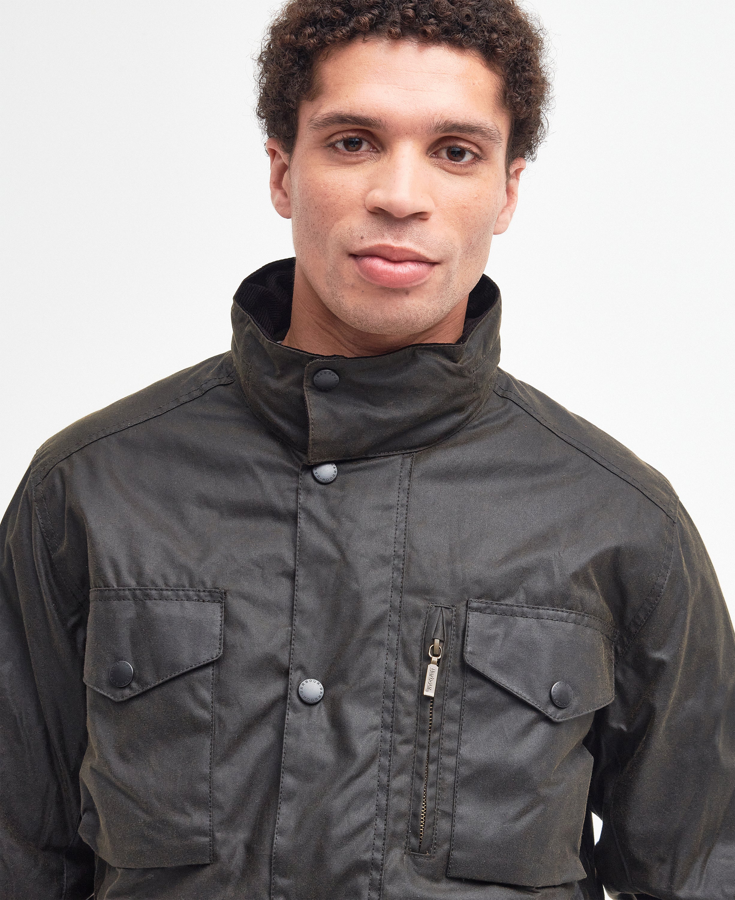 Model wearing the Barbour Sapper Wax Jacket showing the tall collar fastened, vertical dark brass zipper pocket.
