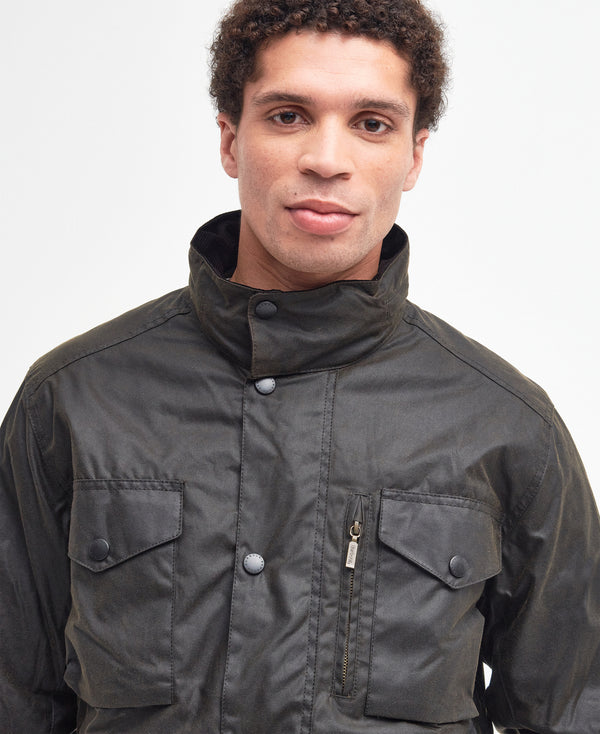 Model wearing the Barbour Sapper Wax Jacket showing the tall collar fastened, vertical dark brass zipper pocket.