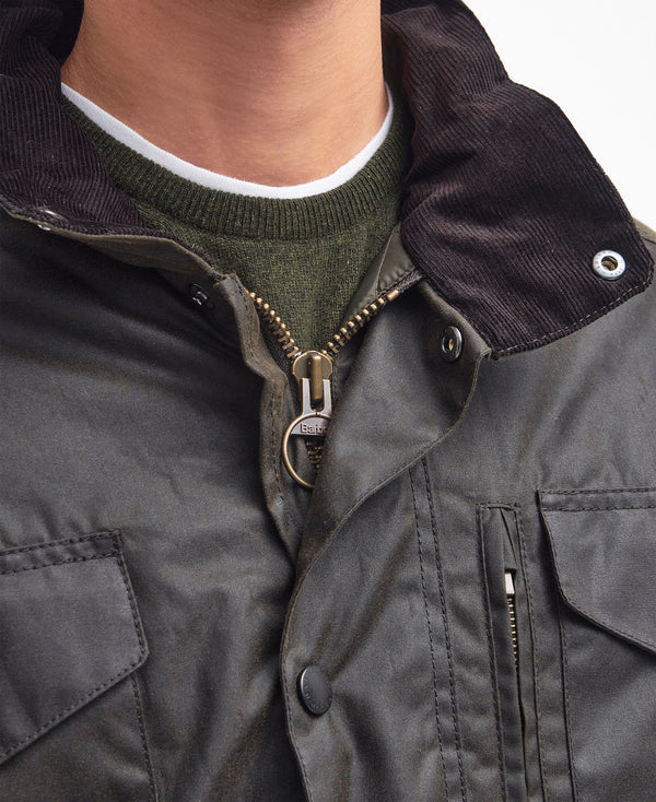 Close-up detail shot of the Barbour Sapper Wax Jacket with brass zipper and buttons, worn over a green shirt.